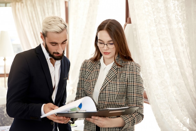 Free photo front view of a handsome businessman and attractive businesswoman who are looking at the file with documents