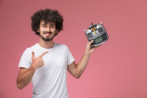 Free photo front view handsome guy pointing out his radio-controller of electronic robot