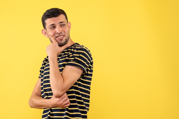 Front view handsome male in black and white striped t-shirt standing on yellow isolated background