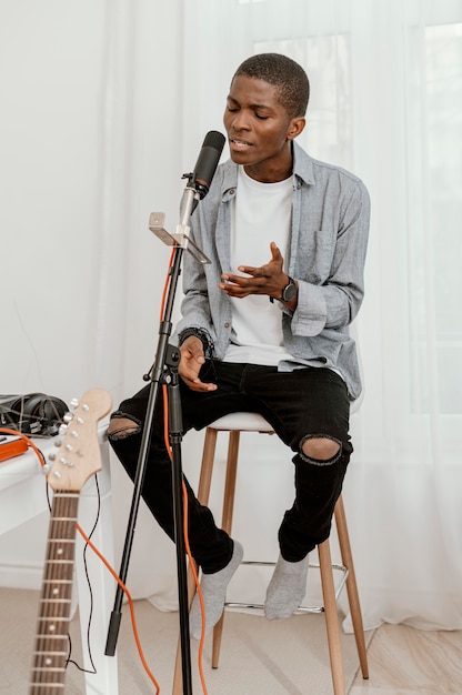 Front view of handsome male musician singing at home with microphone