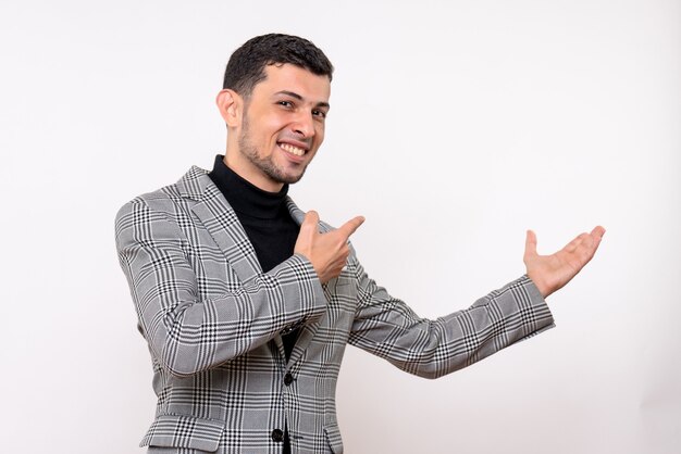 Front view handsome male in suit pointing at behind standing on white background