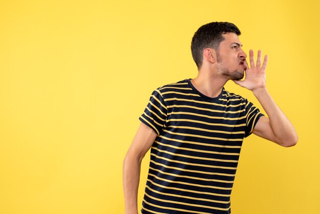 Front view handsome man in black and white striped t-shirt calling someone yellow isolated background