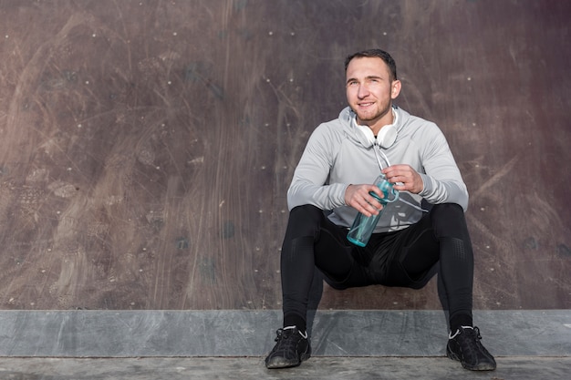 Front view handsome man holding a bottle of water