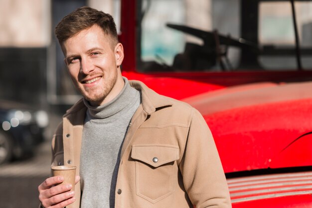 Front view of handsome man posing while holding coffee cup