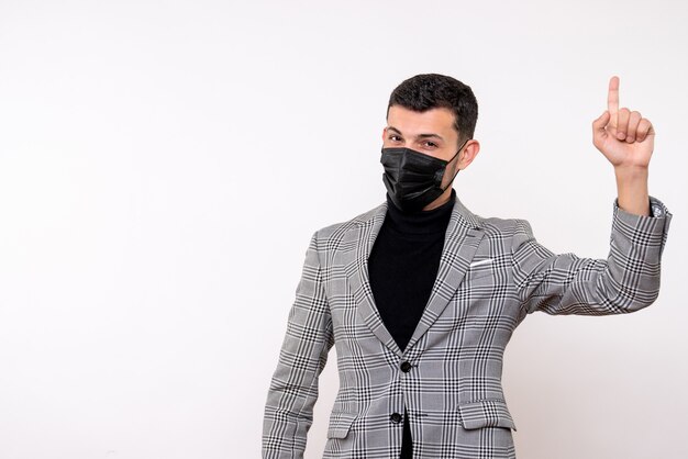 Front view handsome man in suit pointing at ceiling standing on white isolated background