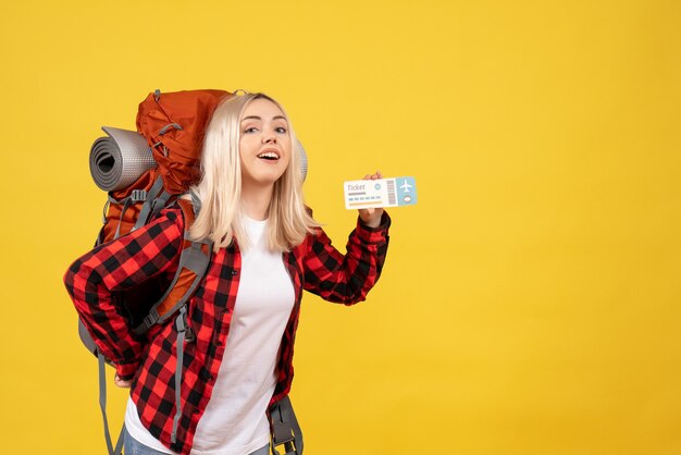 Вид спереди счастливая блондинка с рюкзаком, держащим билет