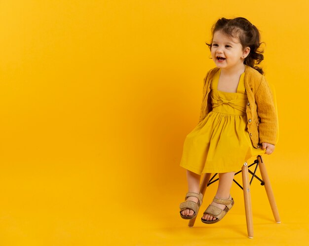 Front view of happy child posing while sitting on chair