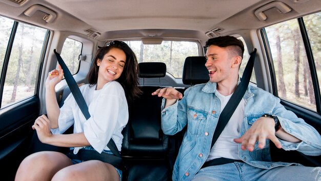 Front view happy couple dancing inside car