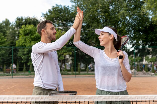テニスコートで正面の幸せなカップル