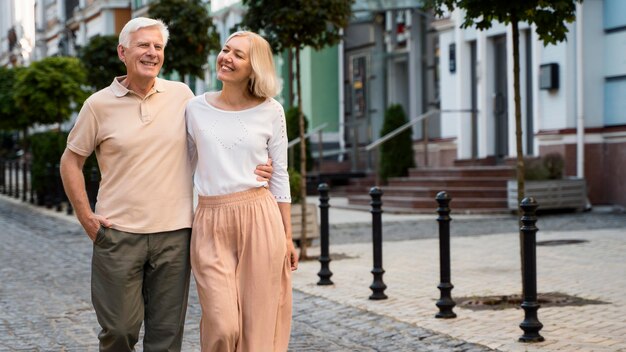 Front view of happy elder couple taking a walk in the city