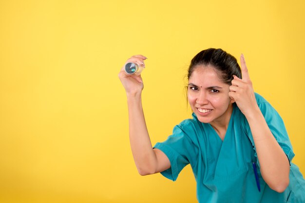 Front view happy female doctor with syringe on yellow background