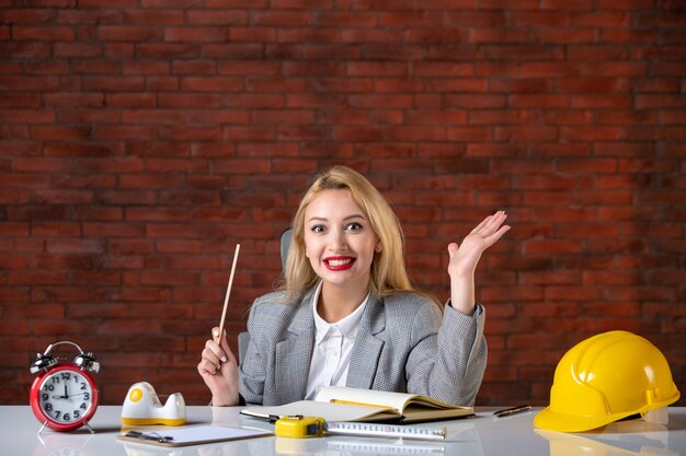 Front view happy female engineer sitting behind her working place