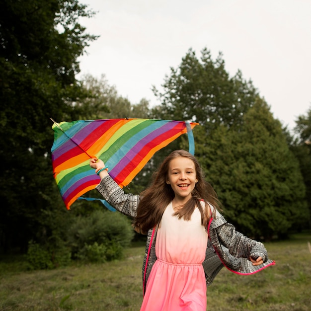 Front view of happy girl having fun with a kite