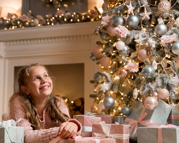 Front view of happy girl with gifts and christmas tree