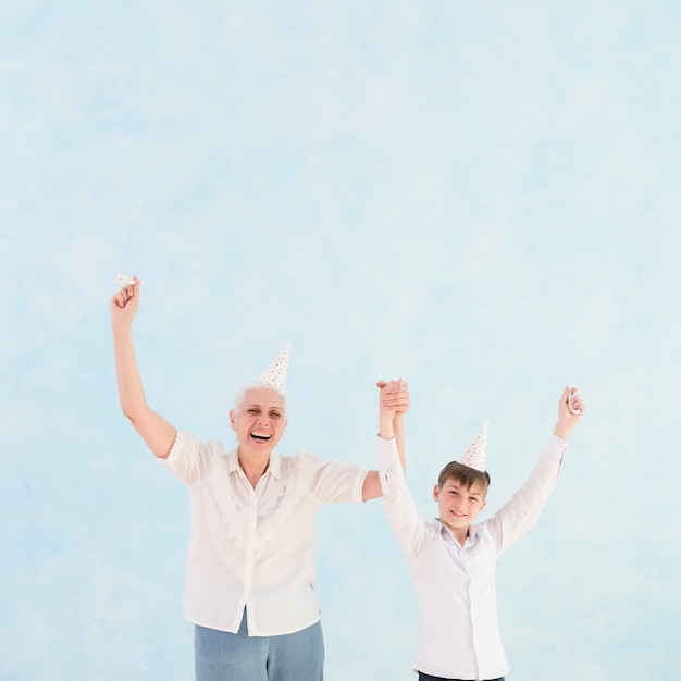 Front view of happy grandmother and grandson with arm raised