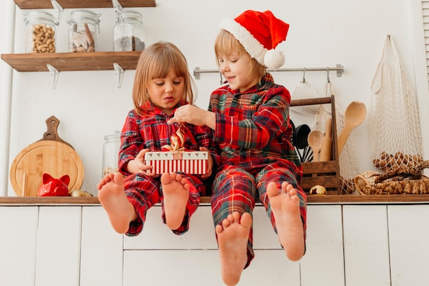 Бесплатное фото Вид спереди счастливые дети, держащие рождественский подарок