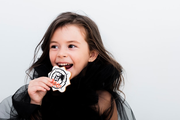 Front view happy little girl eating a cookie