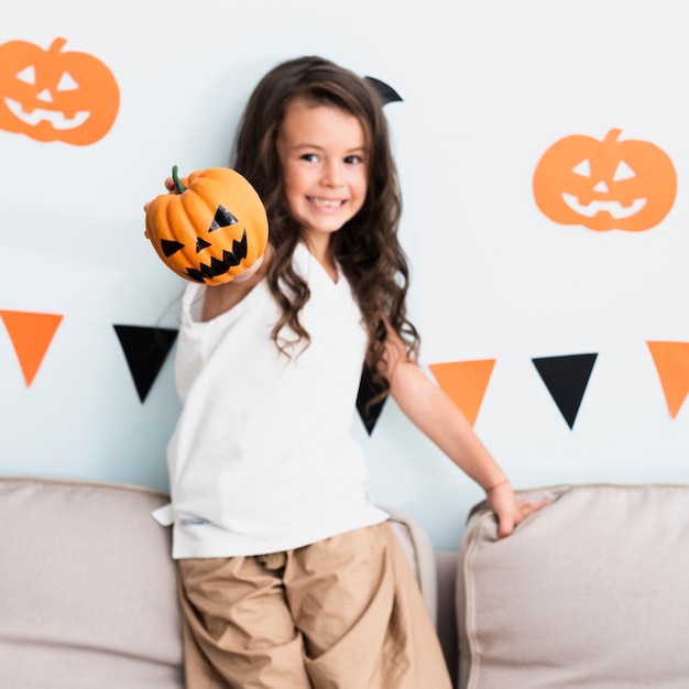 Free photo front view happy little girl holding a pumpkin