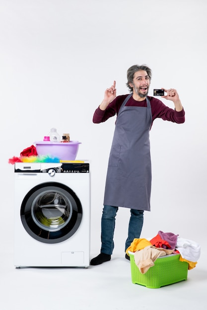 Front view happy man holding card standing near washing machine on white background