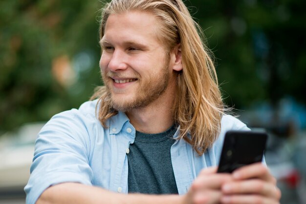 Вид спереди счастливого человека на открытом воздухе с смартфона
