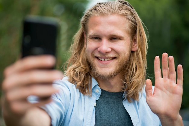 Vista frontale dell'uomo felice che prende selfie all'aperto