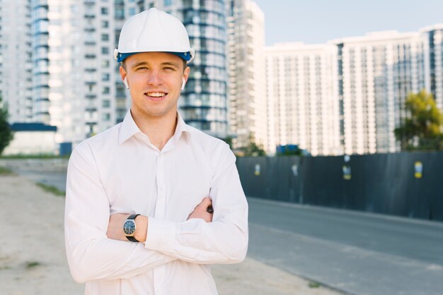 Front view happy man with helmet and crossed arms