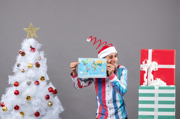 Front view happy man with spiral spring santa hat holding map with both hands