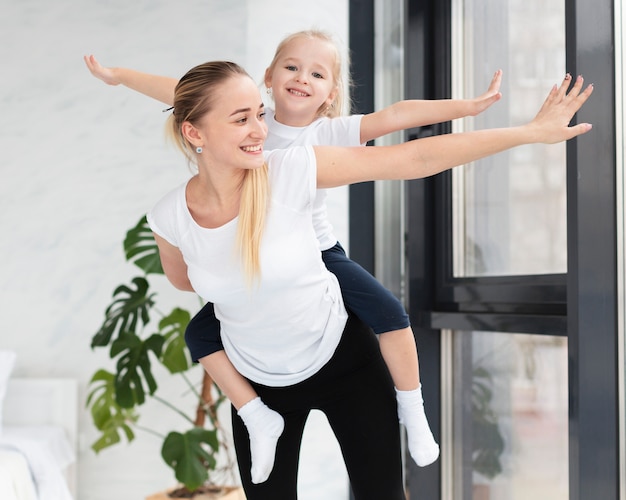 Front view of happy mother and daughter at home exercising