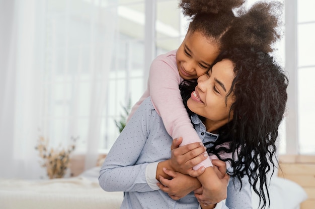 Front view of happy mother playing at home with her daughter