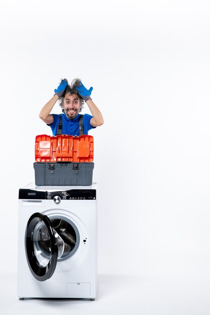 Front view happy repairman holding hair tools bag on washing machine on white space