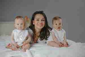 Free photo front view of happy smiled single mother with baby twin girls at home.