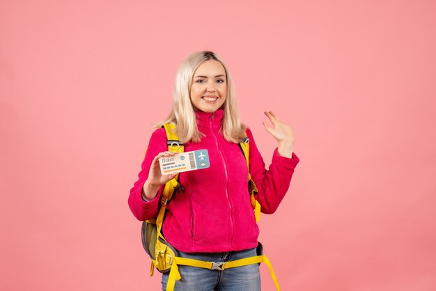 Front view happy woman in casual clothes wearing backpack holding ticket