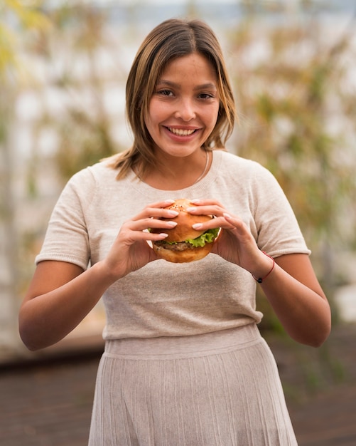 Вид спереди счастливая женщина, держащая гамбургер