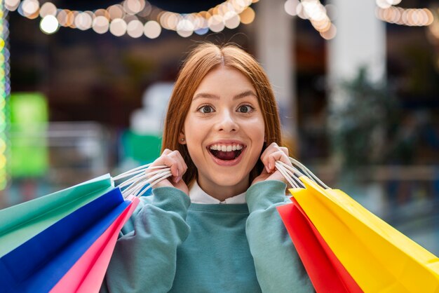 カラフルなバッグを保持している正面の幸せな女