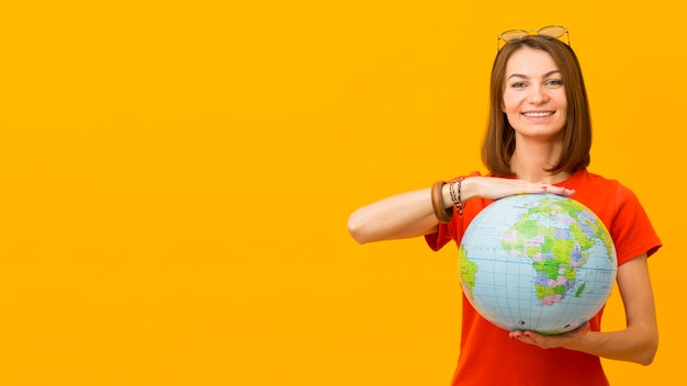 Front view of happy woman holding globe with copy space