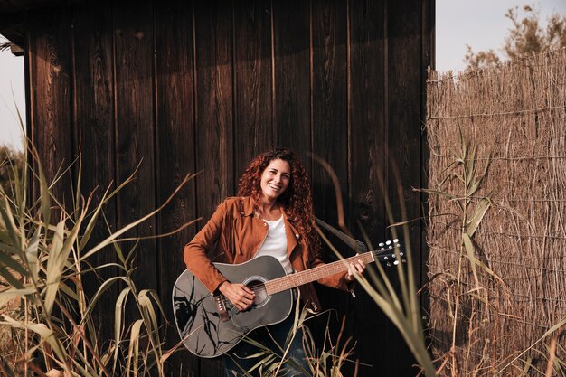 Front view happy woman playing a guitar