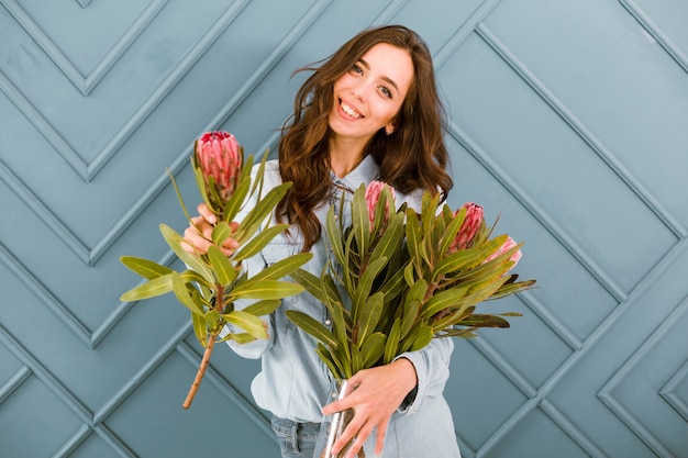 Foto gratuita donna felice di vista frontale che propone con i fiori