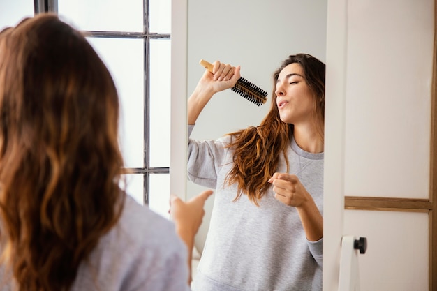 家でヘアブラシに歌う幸せな女性の正面図