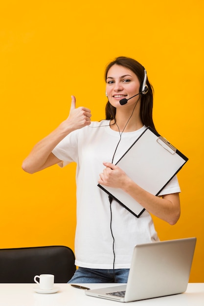 Front view of happy woman wearing headset and giving thumbs up