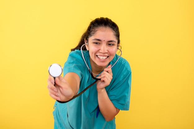 노란색 배경에 청진 기 서와 전면보기 행복 한 젊은 여성 의사
