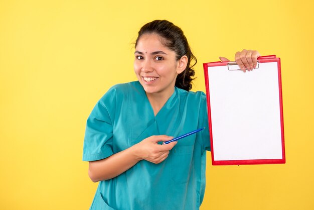 Front view happy young female holding clipboard and pen on yellow background