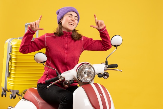 Front view happy young girl on moped with special hand gesture