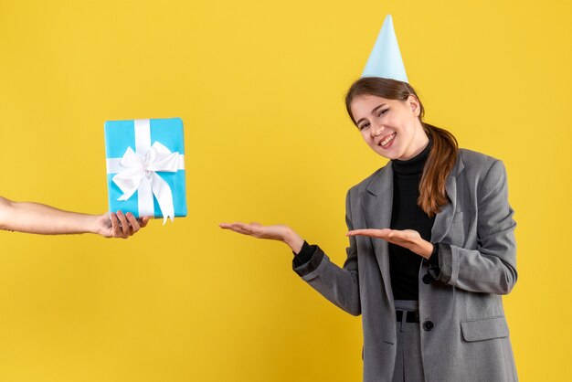 Front view happy young girl with party cap receiving xmas gifts