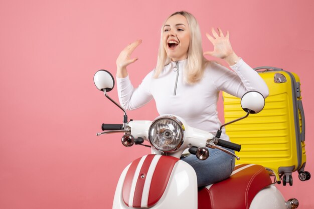 Front view happy young lady on moped raising her hands