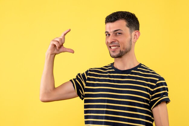 Вид спереди счастливый молодой человек в черно-белой полосатой футболке на желтом изолированном фоне
