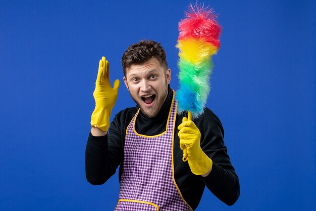 Front view happy young man holding duster on blue space