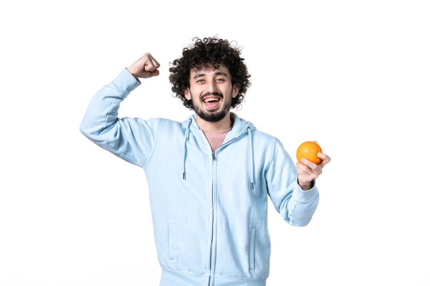 正面図白い背景の上の新鮮なオレンジ色を保持している幸せな若い男健康体の筋肉痩身人間測定減量フルーツ