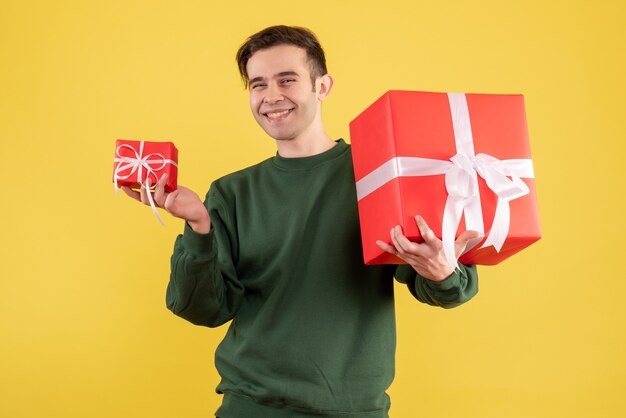 Front view happy young man with green sweater standing on yellow 