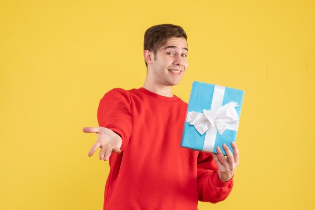 Front view happy young man with red sweater standing on yellow 