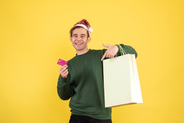 Front view happy young man with shopping bags standing on yellow 